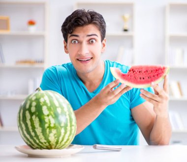 Evde karpuz yiyen bir adam.