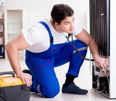 Tamirci müteahhit DIY konseptinde buzdolabını tamir ediyor.