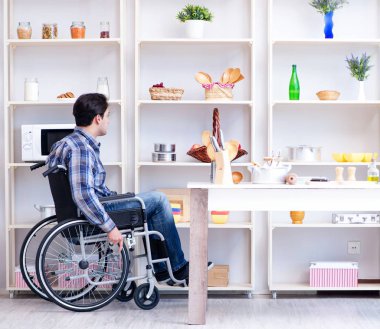 Engelli genç koca mutfakta çalışıyor.