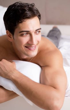Genç yakışıklı gömleksiz adam gösteren çıplak gövde seksi yatakta s