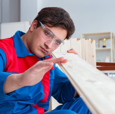 Genç marangoz ahşap kalaslarla çalışıyor.