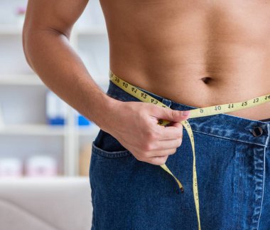 Kilo verme konseptinde büyük beden pantolon giyen bir adam.