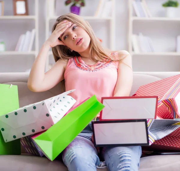 Молодая женщина с пакетами для покупок в помещении дома на диване — стоковое фото