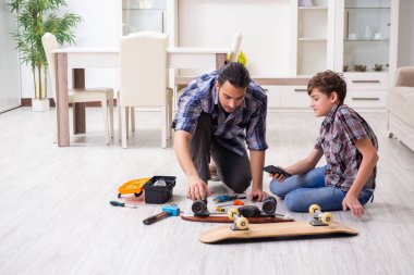 Genç baba oğluyla kaykay tamir ediyor.