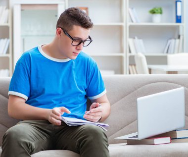 Sınavlara hazırlanan genç öğrenci kanepede ders çalışıyor.