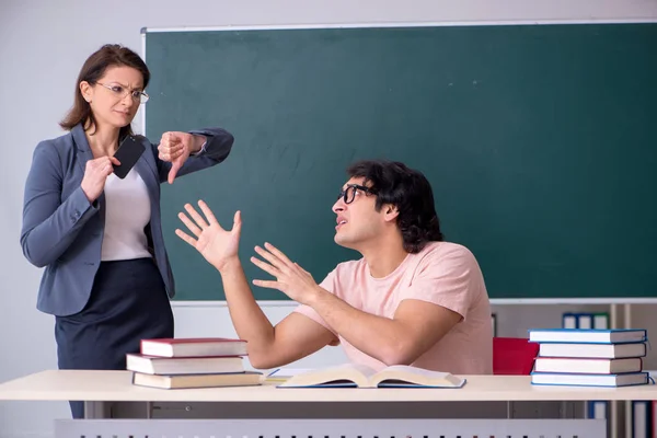 Old female teacher and male student in the classroom — Stock Photo, Image