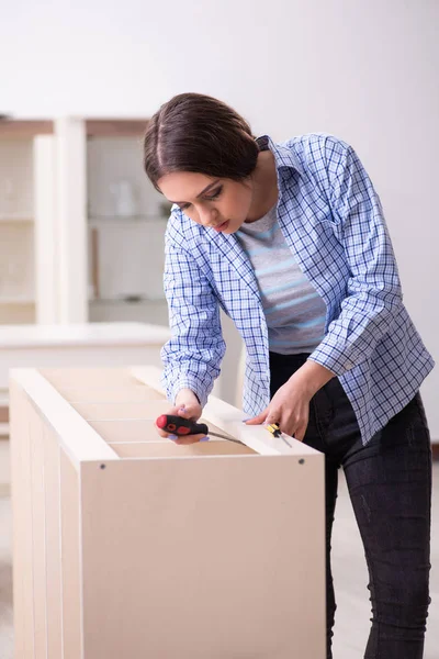 Giovane bella donna che assembla mobili a casa — Foto Stock