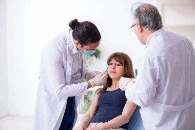 Plastik cerrahi konseptinde iki erkek doktor ve genç kadın.