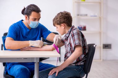 Genç çocuk hastanede doktoru ziyaret ediyor.