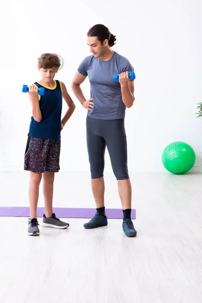 Jovem pai e seu filho fazendo exercícios — Fotografia de Stock