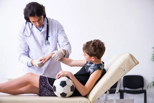 Chłopiec piłkarz odwiedzając młodego lekarza traumatologa — Zdjęcie stockowe