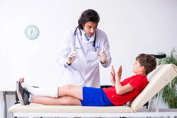 Beengewonde jongen op bezoek bij jonge dokter traumatoloog — Stockfoto