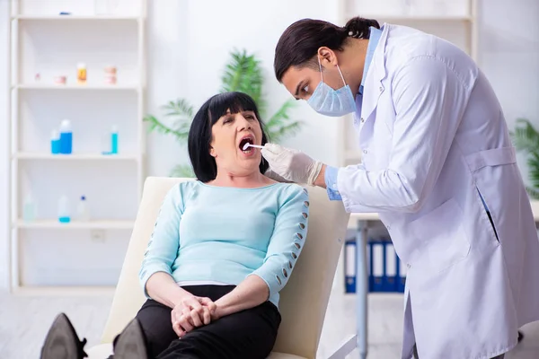 Vieille femme visitant jeune médecin dentiste — Photo