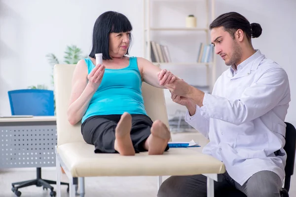 Young male doctor examining old female patient — Stock Photo, Image