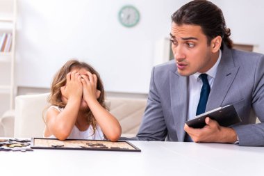 Çocuk psikoloğu küçük bir kıza bakıyor