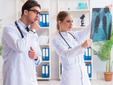 İki doktor teşhis için hastanın röntgen görüntülerini inceliyor.