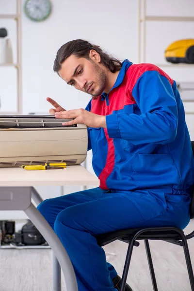 Jovem empreiteiro masculino reparando ar-condicionado na oficina — Fotografia de Stock