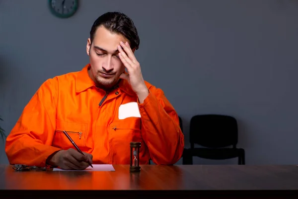 Junger Häftling sitzt in dunklem Raum — Stockfoto