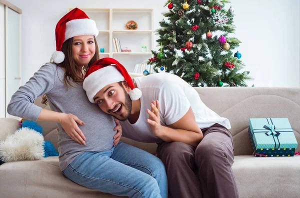 Молодая семья, ожидающая ребенка, празднующего Рождество — стоковое фото