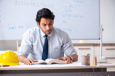Genç erkek mimar beyaz tahtanın önünde.