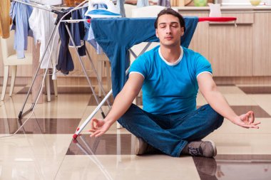 Genç adam evde çamaşır ütülüyor.