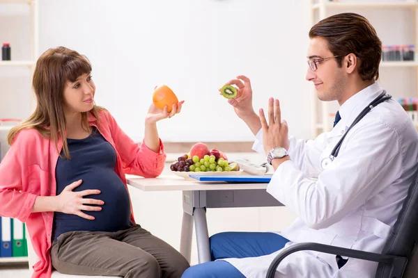 Pregnant woman visiting doctor discussing healthy diet — Stock Photo, Image