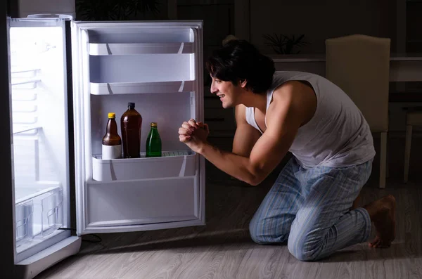 Человек нарушает диету ночью возле холодильника — стоковое фото