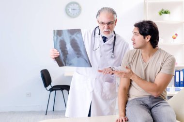Genç adam yaşlı erkek doktor radyoloğu ziyaret ediyor.