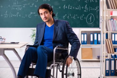 Yakışıklı delikanlı kara tahta önünde tekerlekli sandalyede