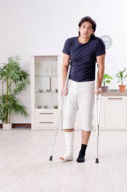 Evde acı çeken bacağı yaralı genç adam.