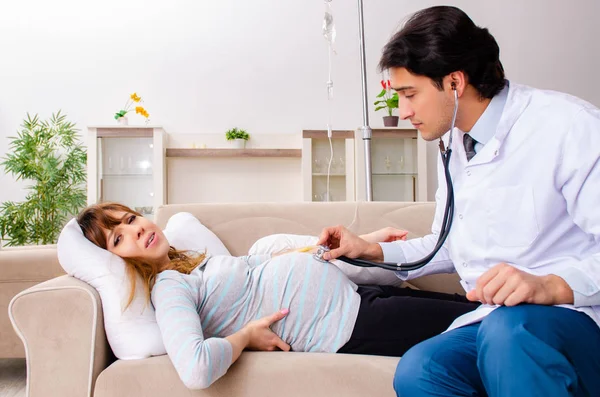 Jonge knappe dokter bezoekt zwangere vrouw thuis — Stockfoto