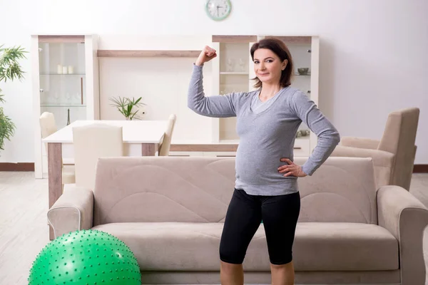 Mulher grávida envelhecida fazendo exercícios em casa — Fotografia de Stock