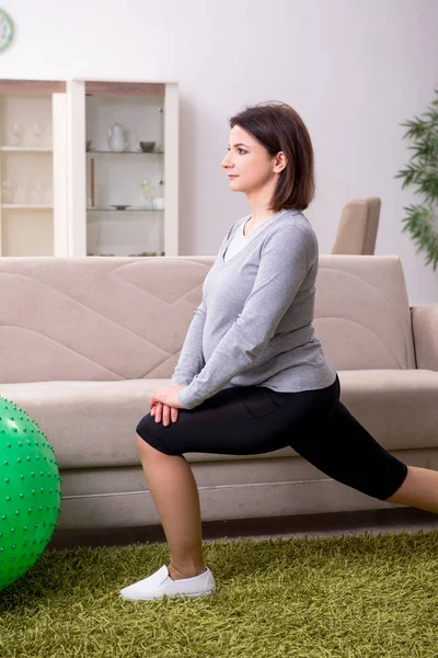 Verouderde zwangere vrouw doet oefeningen thuis — Stockfoto