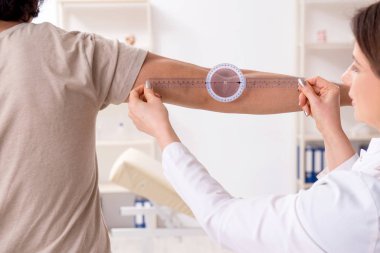 Kadın doktor hastaları goniyometre ile kontrol ediyor.