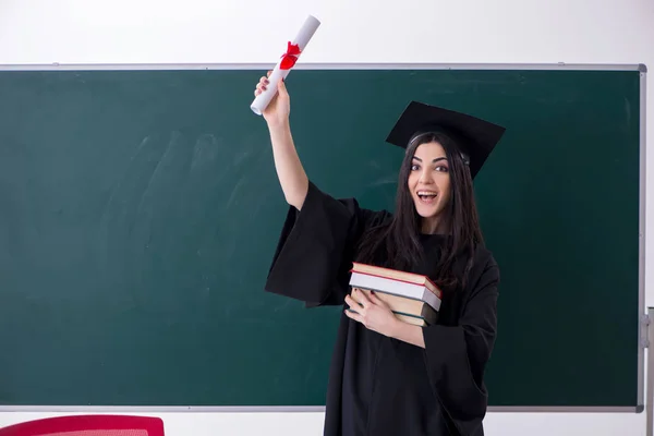 Estudiante graduada frente al tablero verde — Foto de Stock