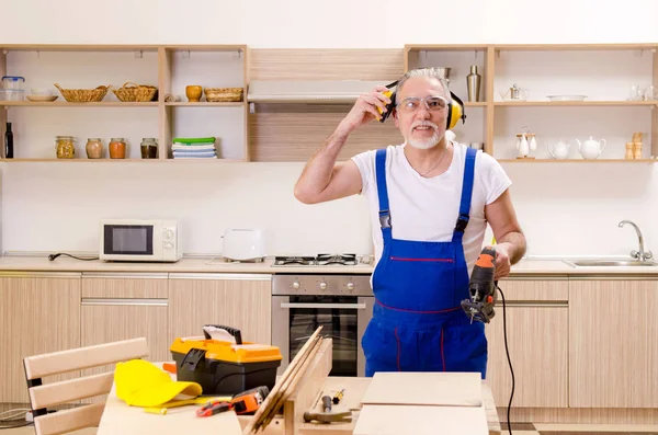 Пожилой подрядчик ремонтник, работающий на кухне — стоковое фото