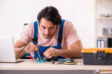 Genç bir erkek müteahhit bilgisayar tamir ediyor.