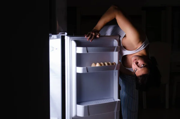 Чоловік розбиває дієту вночі біля холодильника — стокове фото