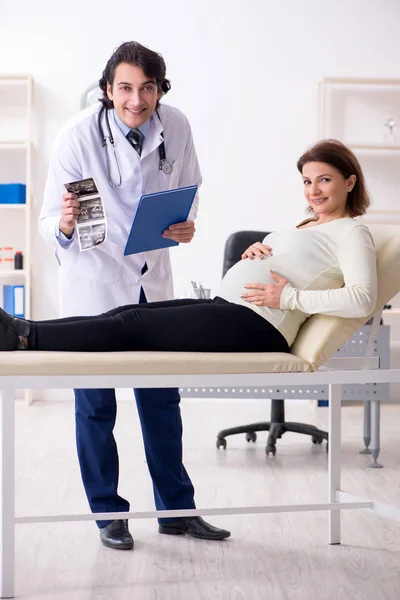 Velha mulher grávida visitando jovem médico masculino — Fotografia de Stock