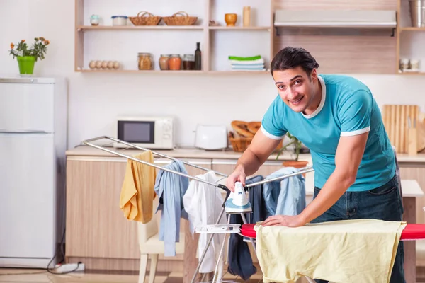 Joven marido haciendo planchado de ropa en casa — Foto de Stock