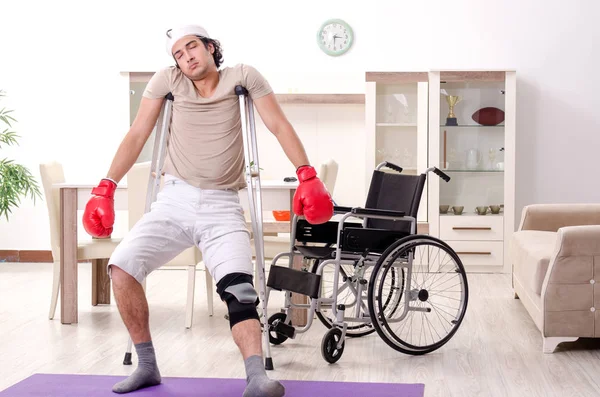 Injured young man doing exercises at home — Stock Photo, Image