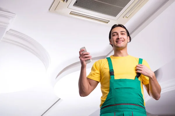 Mladý opravář opravuje stropní klimatizační jednotku — Stock fotografie