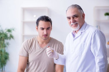 Erkek hasta aşı aşısı için doktoru ziyaret ediyor.