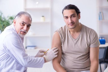 Erkek hasta aşı aşısı için doktoru ziyaret ediyor.