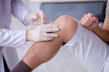 Erkek hasta aşı aşısı için doktoru ziyaret ediyor.