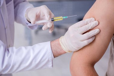 Erkek hasta aşı aşısı için doktoru ziyaret ediyor.