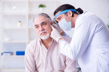 Erkek hasta doktor otolaryngologu ziyaret ediyor.