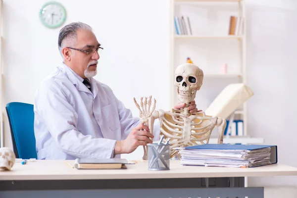 Verouderde mannelijke arts met skelet — Stockfoto