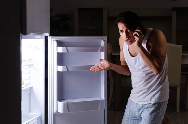 Man breaking diet at night near fridge — Stock Photo, Image