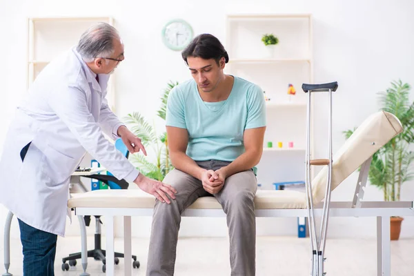 Jovem perna machucado paciente masculino visitando antigo médico — Fotografia de Stock